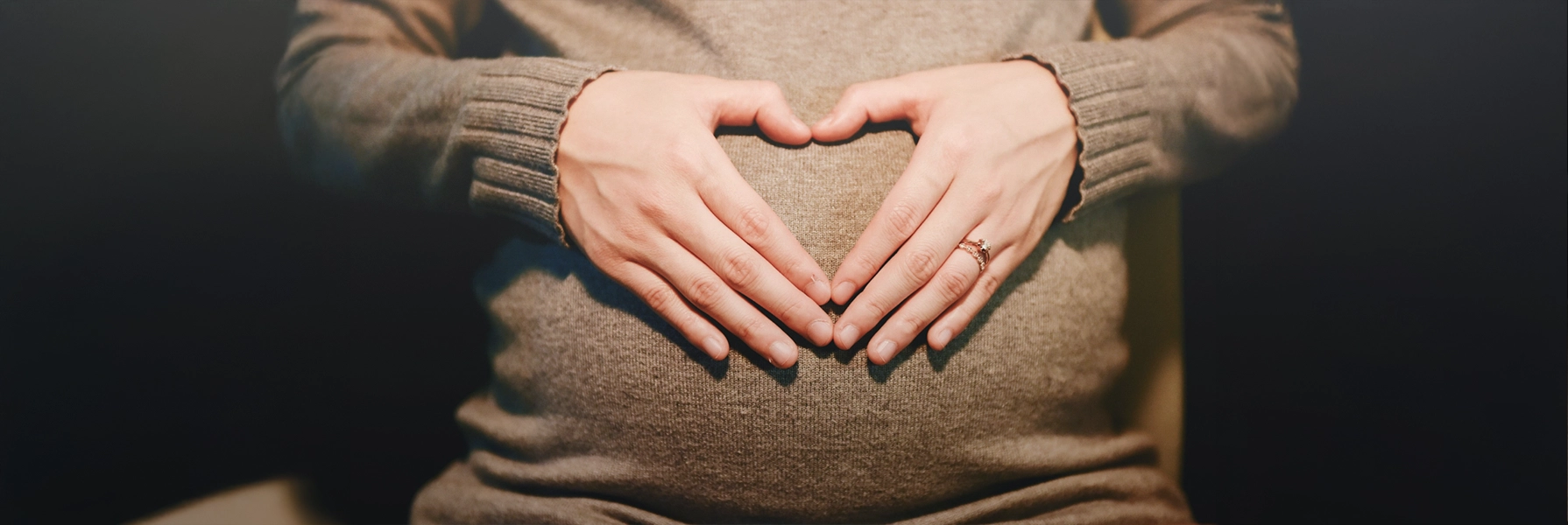 Hands forming a heart over a baby bump, highlighting the importance of HCG levels in early pregnancy detection.