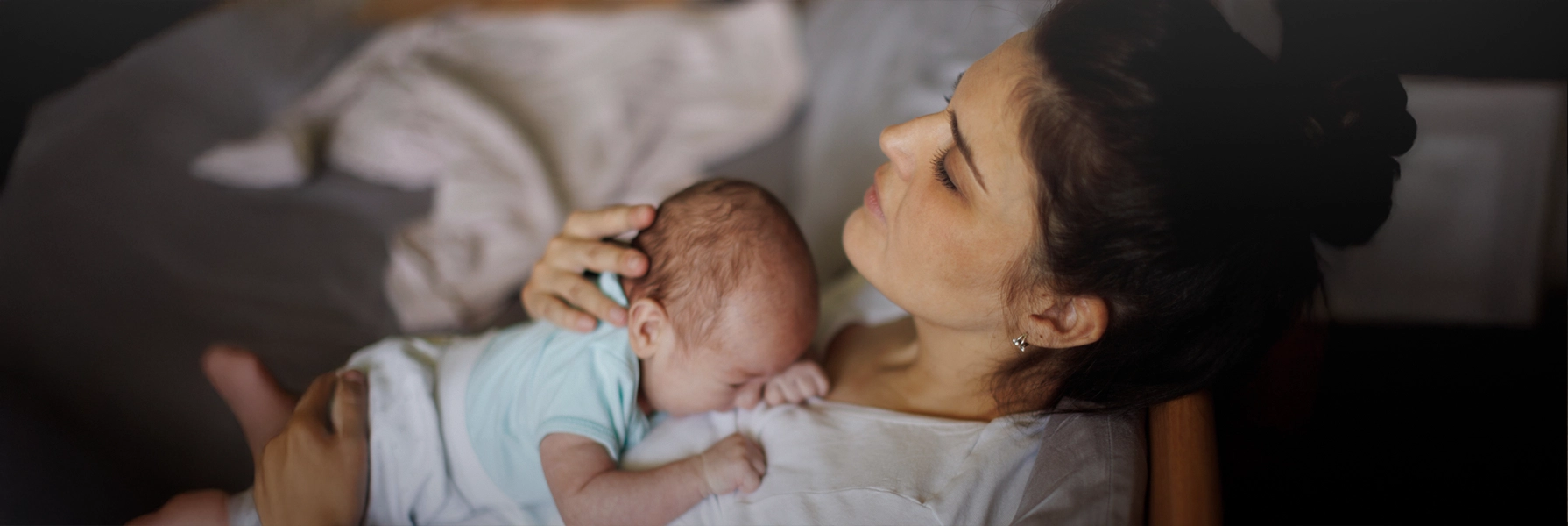 A mother resting in bed with her newborn, highlighting the emotional and physical aspects of postpartum recovery